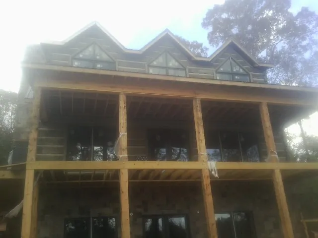 Dormers and porch framing on a large log home under construction — Roof Coating work by our crew in Beechgrove