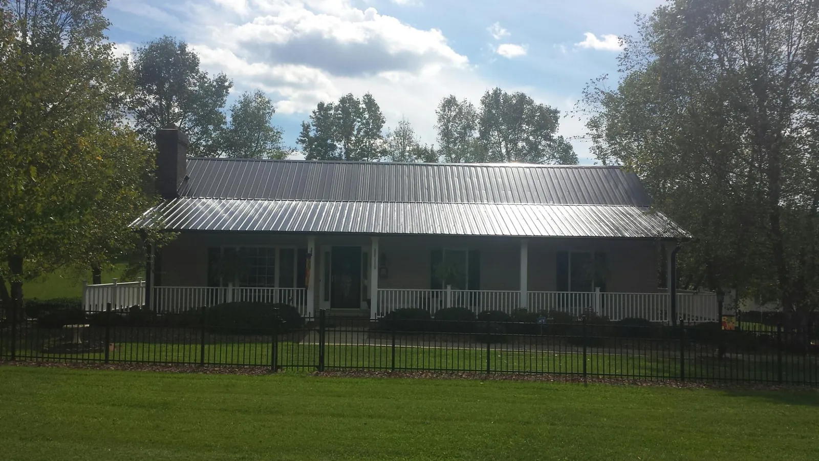 Gray metal roof on a brick ranch with a full width front porch — Gutter Guard Installation work by our crew in Beechgrove