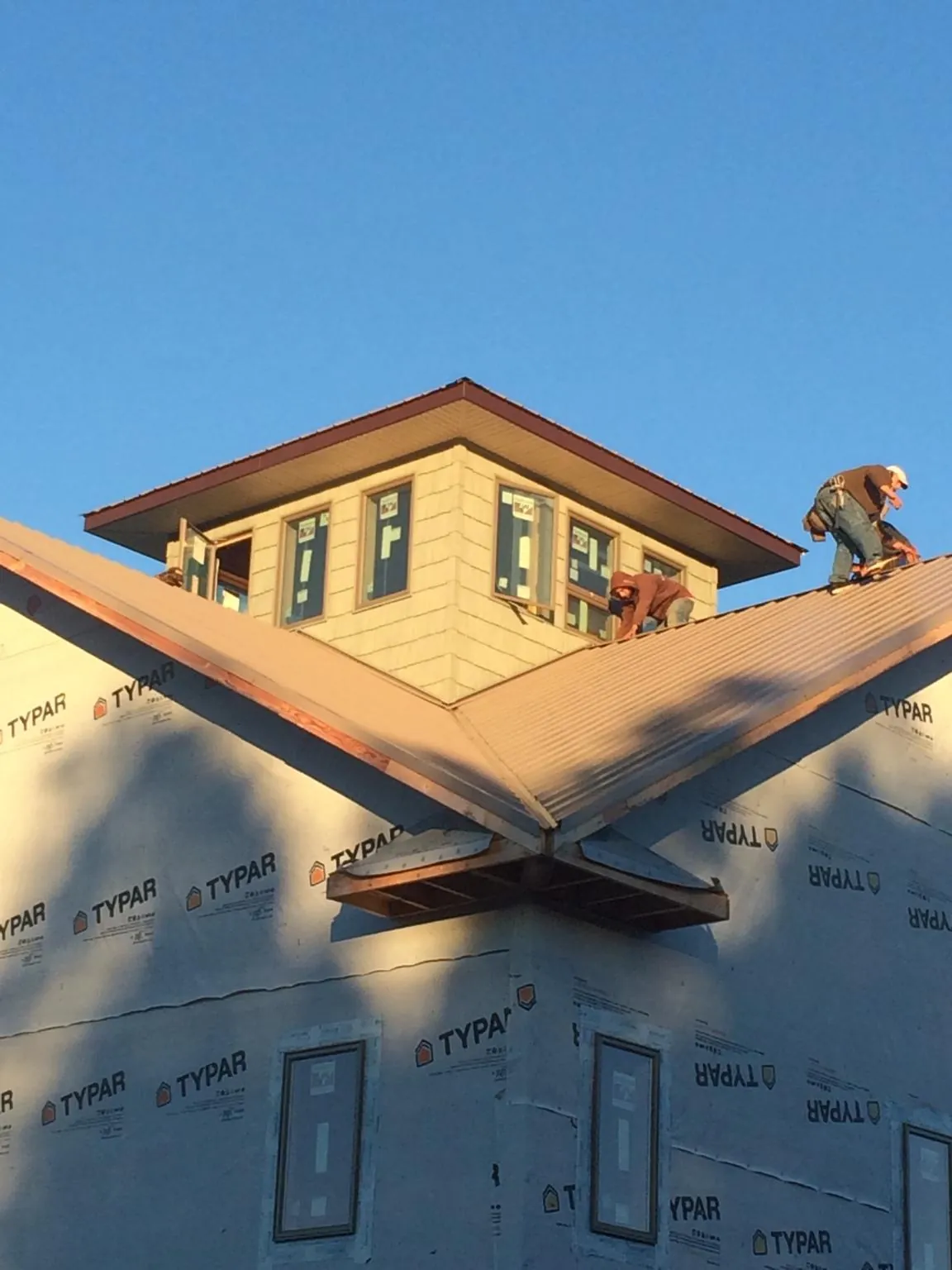 Roofers working around a rooftop cupola on a new metal roof at sunset — Roof Waterproofing in Beechgrove by Roofing Brothers